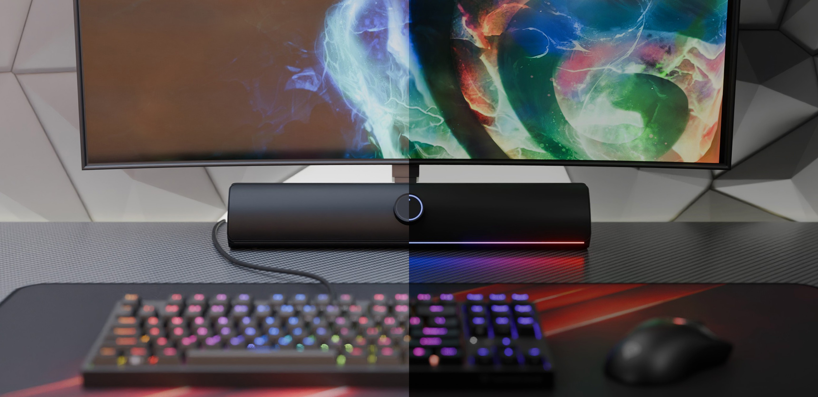 Μαύρη ηχομπάρα Bluetooth τοποθετημένη κάτω από μια πολύχρωμη οθόνη, με πληκτρολόγιο και ποντίκι gaming RGB σε ένα γραφείο
